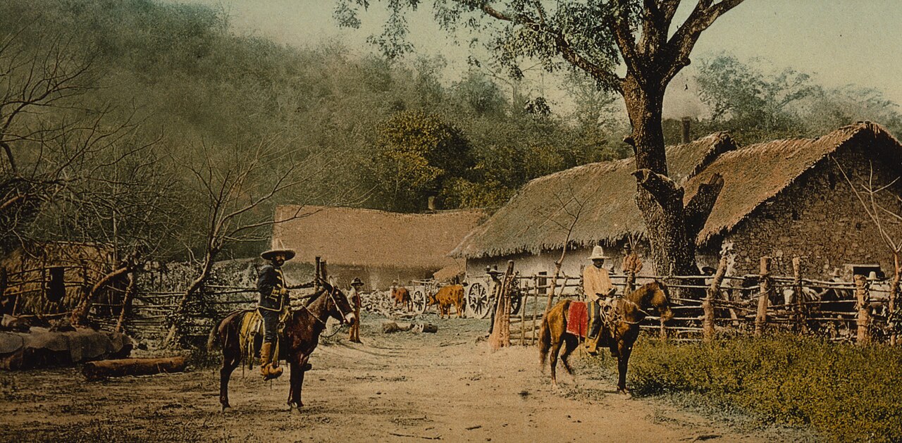 Hand-coloured photograph of a rural hacienda with thatched buildings and horsemen