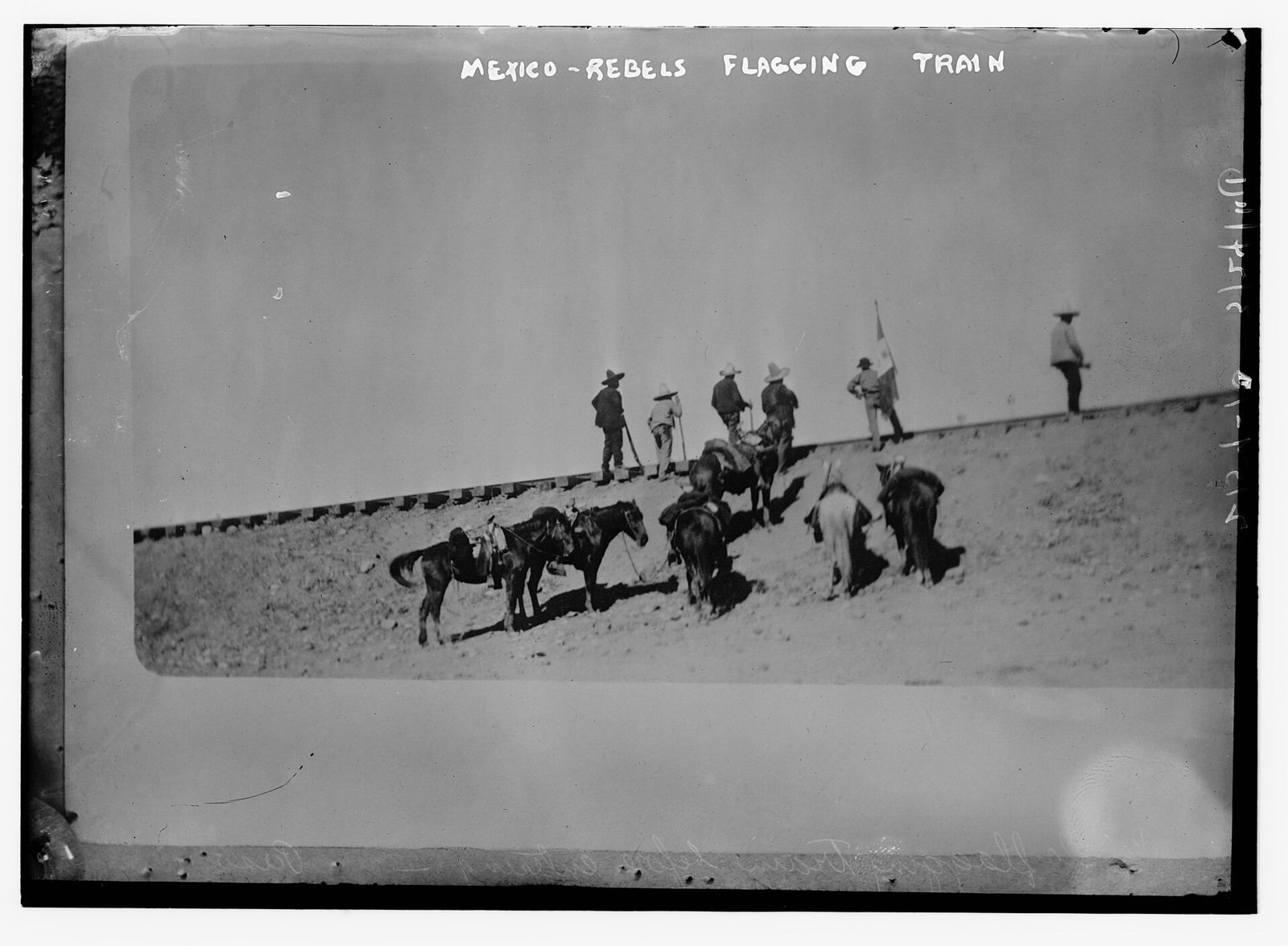 Mounted rebels and men on foot beside a raised railway embankment, signalling a train